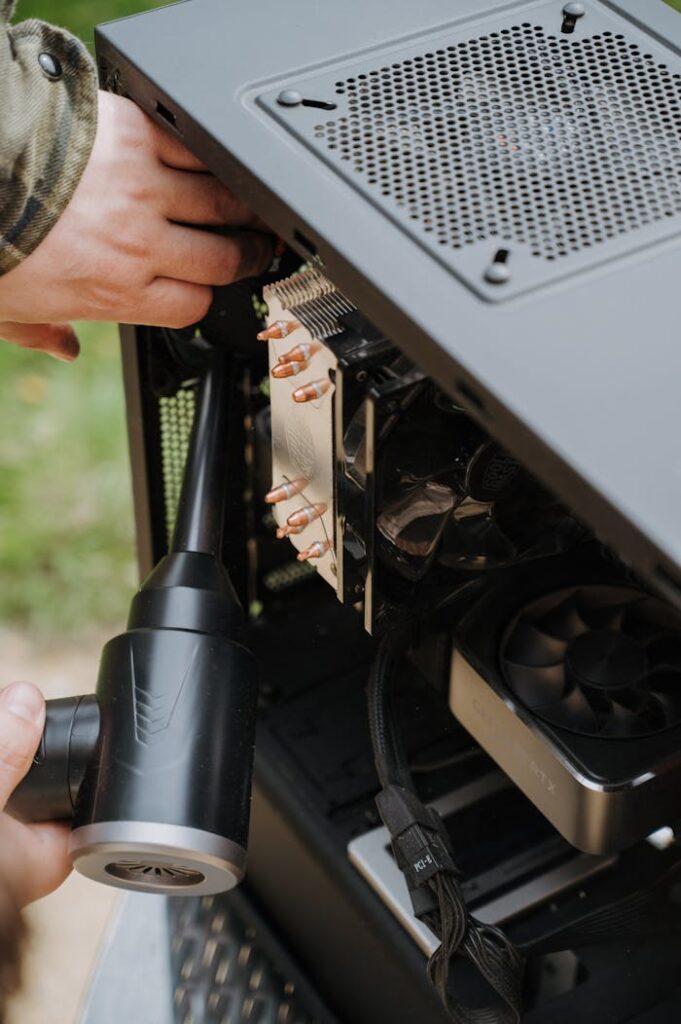 Close-up of hands cleaning the interior of a PC case with a duster, focusing on computer care and maintenance.